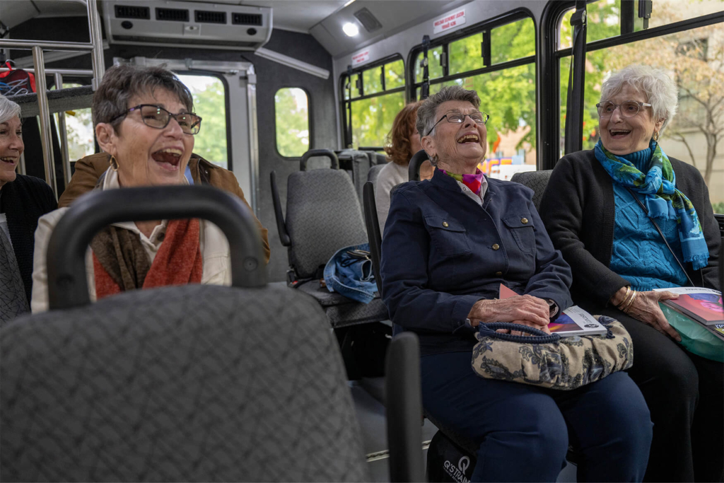 Three women laugh on a bus together