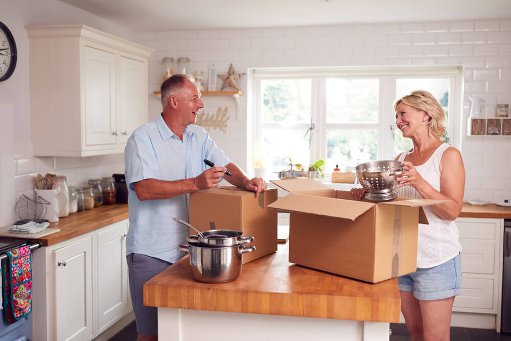 An older couple packs up their kitchen into boxes as they downsize