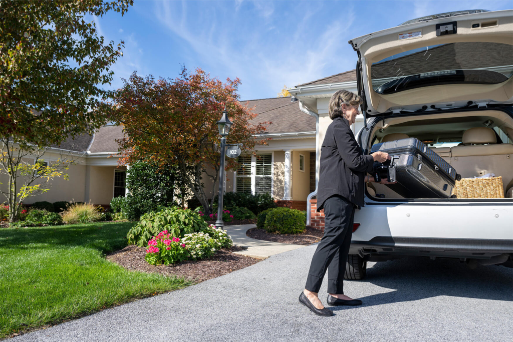 Woman loads suitcase into the back of her car as she prepares to downsize