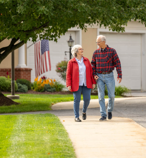 Couple holding hands and walking through Woodcrest Villa campus