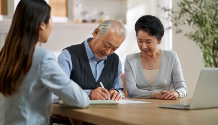 Couple signing a CCRC contract at a table with another woman watching