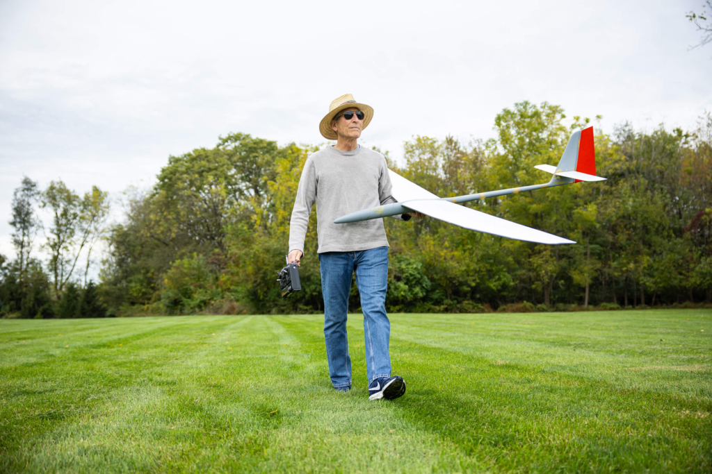 A resident in the Bloom Wellness Woodcrest Villa program holds a model plane and walks in a field
