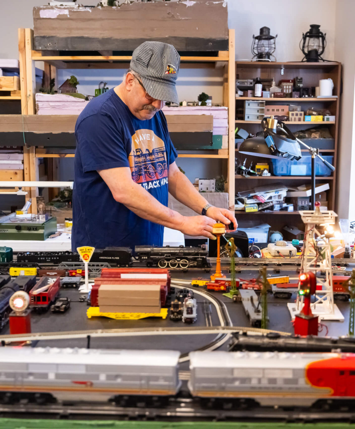 A male resident in the Bloom Wellness Woodcrest Villa program works in a model train room