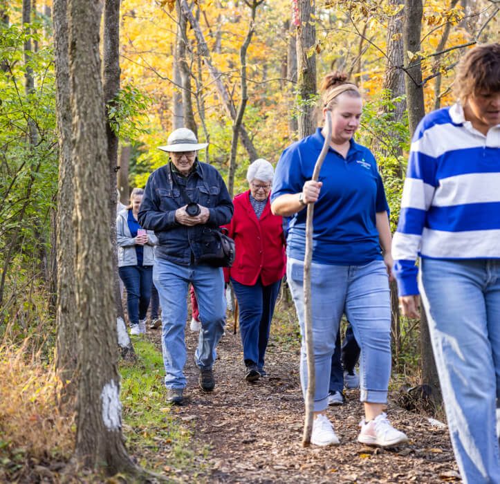 A group of people walk on a nature trail as part of Bloom Wellness at Woodcrest Villa