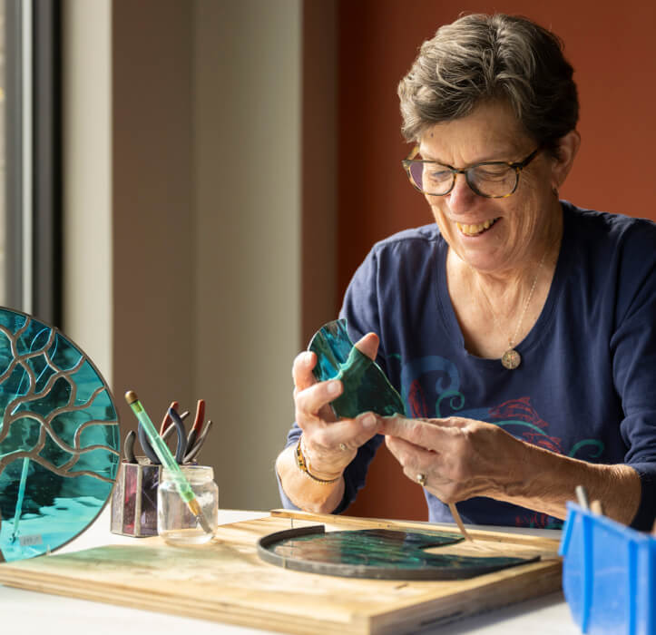 A woman creates a stained glass piece of art as part of Bloom Wellness at Woodcrest Villa