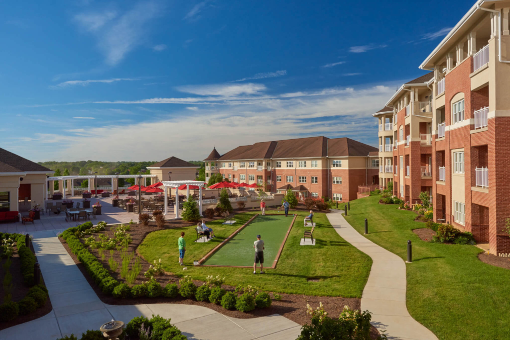 A few senior living residents play bocce ball on a sunny day on the Woodcrest Villa campus