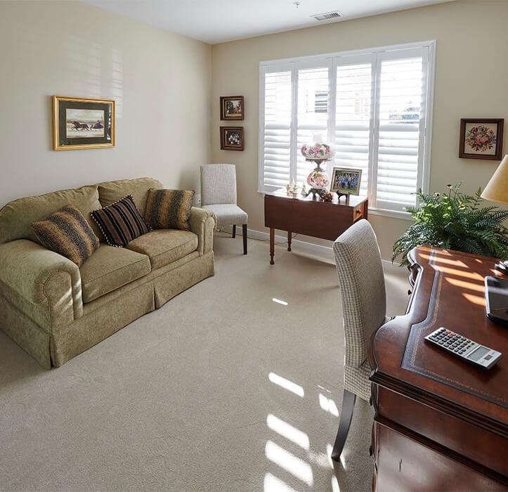 2-bedroom senior apartment with a green couch against one wall and a wooden desk at the other