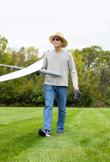 John, a resident of a retirement community in Lancaster County, PA, walks through a field holding a model plane