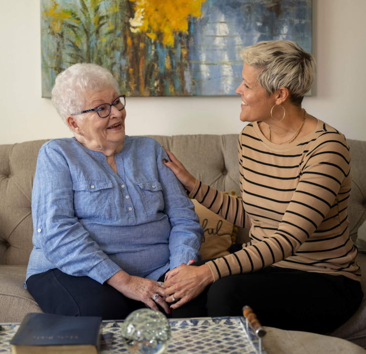 A senior independent living resident in Lancaster, PA sits on a couch with a female staff members and they both smile