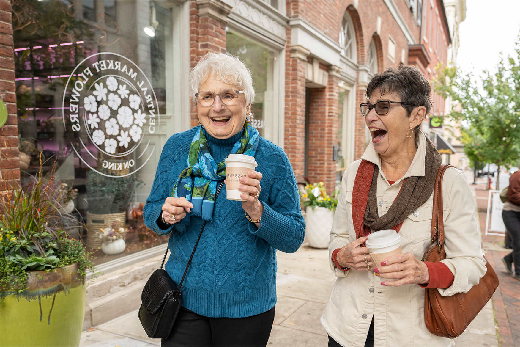 Two Woodcrest Villa residents walk down the sidewalk in Lancaster City, holding coffees